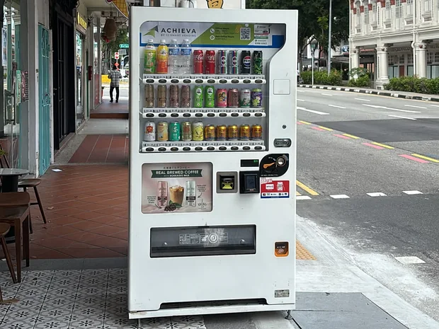An Achieva drinks machine on a shophouse corner beside a cafe in Singapore